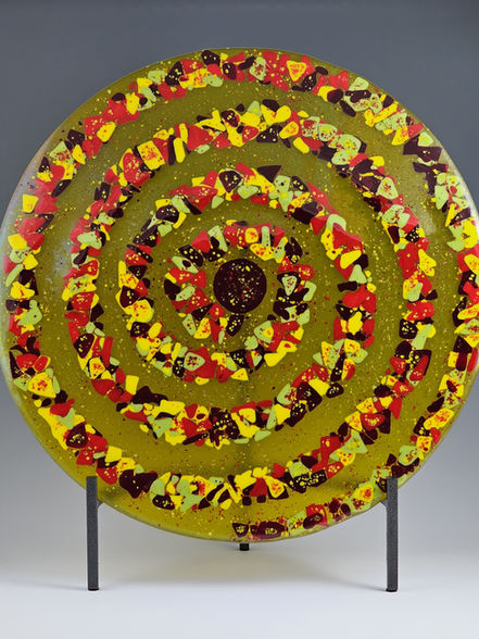 Handmade 18 " flat disc sculpture with a cosmic spiral design in red, yellow, orange, green and gold iridized fused glass.