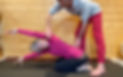 Serge guide Cath dans une variante de Balasana, il ajuste son dos.