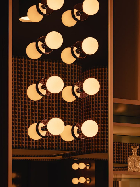 Warm ambient lighting in a luxury restaurant bathroom featuring decorative globe sconces and soft illumination that enhances atmosphere and guest experience.