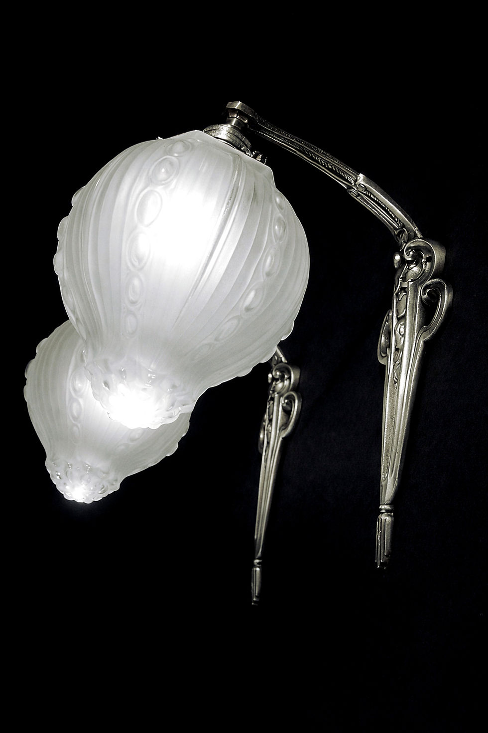 Miniature : Paire d’appliques Georges Leleu allumées diffusant une lumière douce à travers leurs globes en verre pressé satiné.