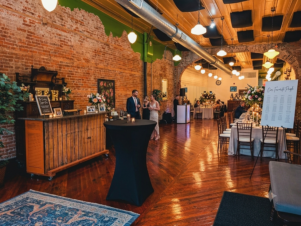 Elegant wedding reception in a brick hall with warm lights, floral tables, guests mingling, and a sign reading Our Favorite People