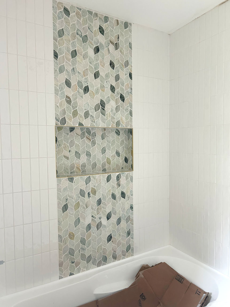Bathroom renovation with green and gold luxury wallpaper, white stacked tile and green marble tile, black leathered granite and delta champagne bronze fixtures.