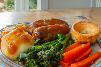 Sausages and mash with some veggies on a plate