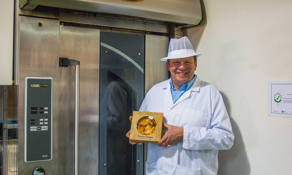 A man stood in front of an oven holding a pie