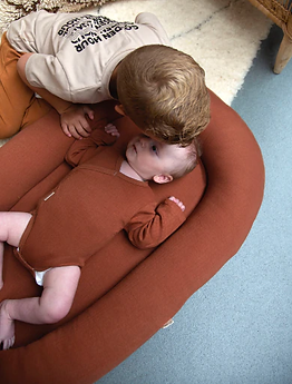 Kindje ligt in little indians babynestje donkerrood.webp