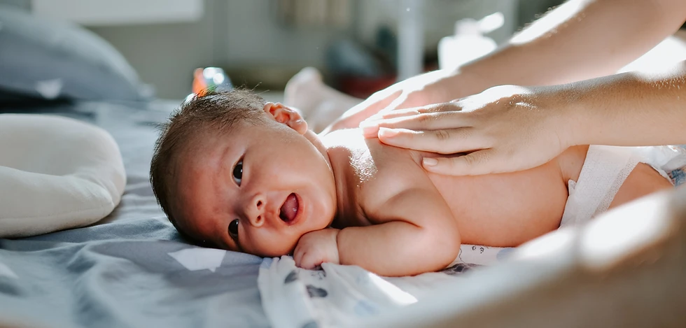 Süßes Baby liegt auf dem Bauch und bekommt eine Rückenmassage beim Windelwechsel.webp