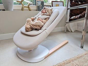 Baby ligt in Stokke Yoga wipstoeltje in woonkamer.jpg