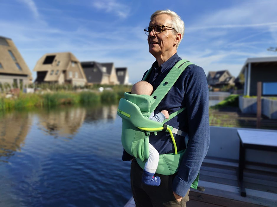 Frank met baby in NIMBEL draagzak groen buiten aan het water.jpg