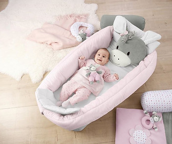 Baby ligt in groot babynestje van Sterntaler met knuffeltje.jpg