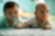 Twee lieve baby's liggen op hun buik met speen in mond.jpg