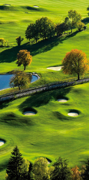 Dronefoto over grønn golfbane med innsjøer og åser