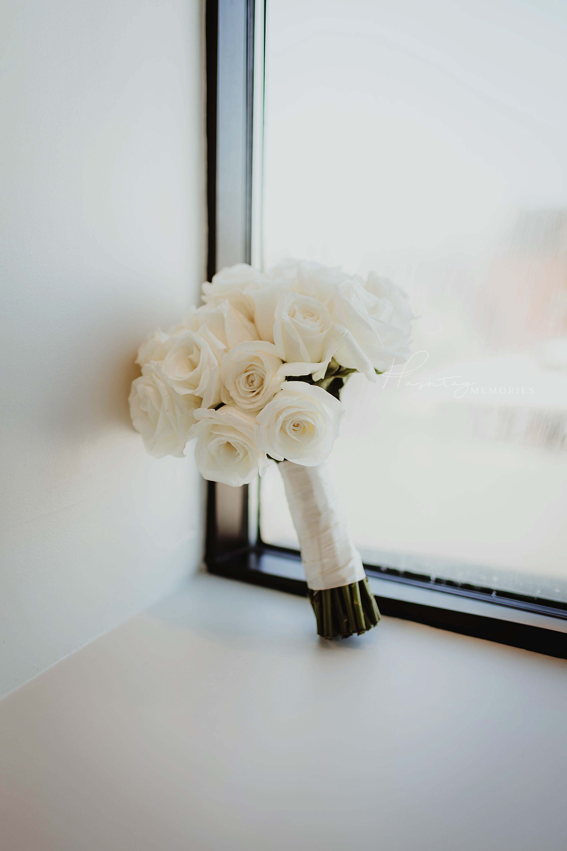 white rose wedding bouquet sits in window frame, wrapped in white satin ribbon for vintage styled wedding day in kokomo