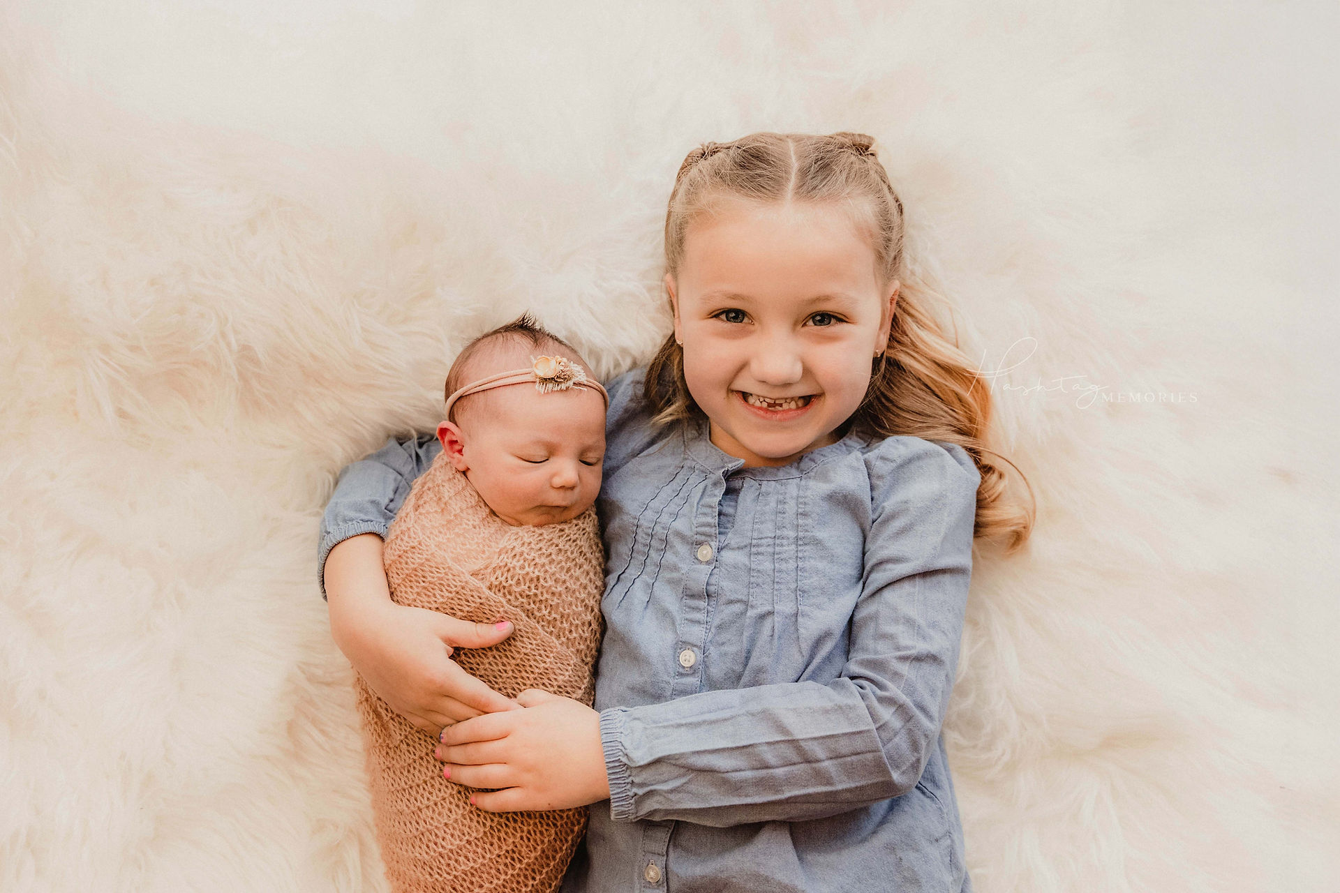 newborn baby girl snuggles with big sister during newborn photography session in cicero indiana