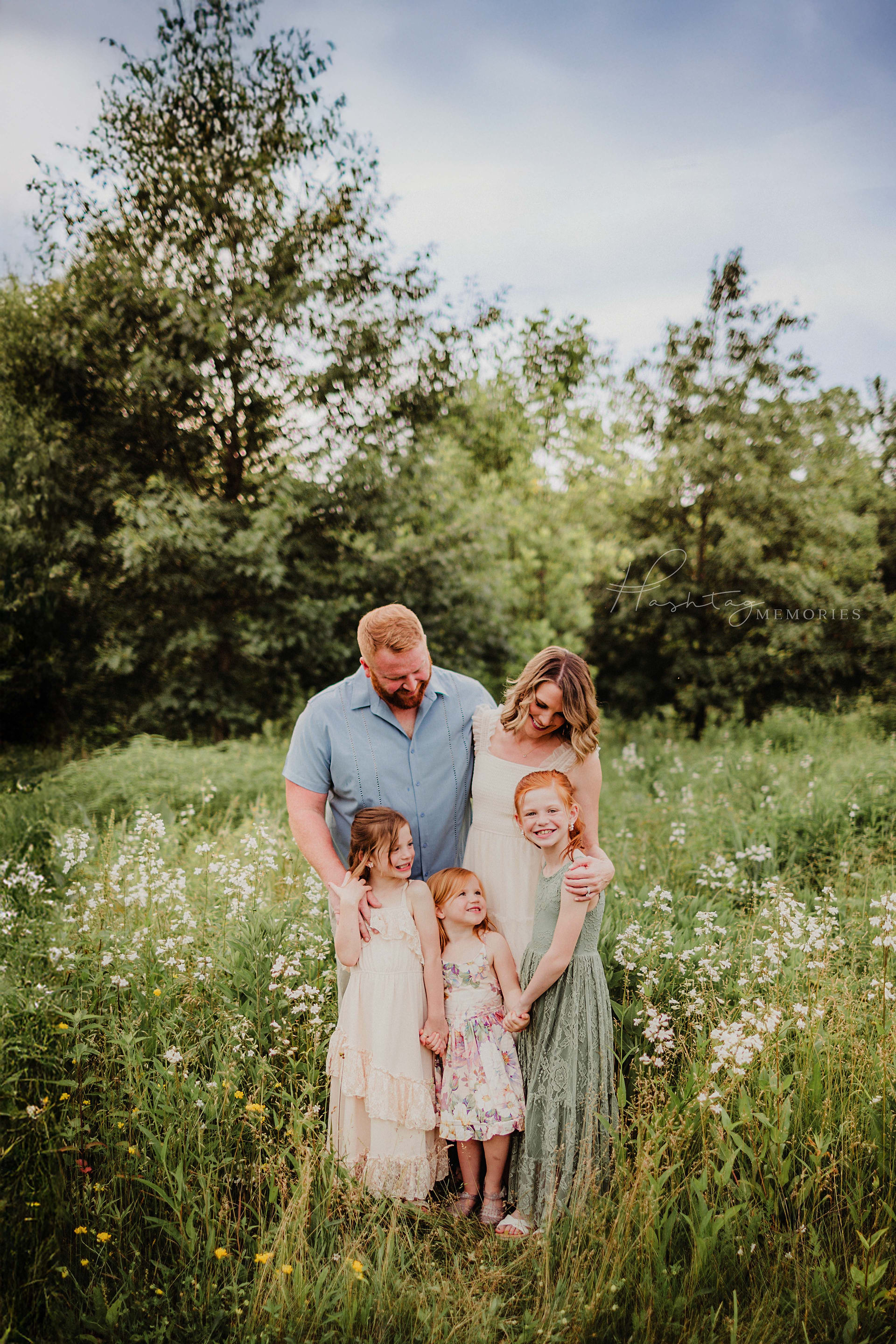 Family of five, mom, dad, and three daughters smile in flower field, snuggling during family photos in cicero, indiana