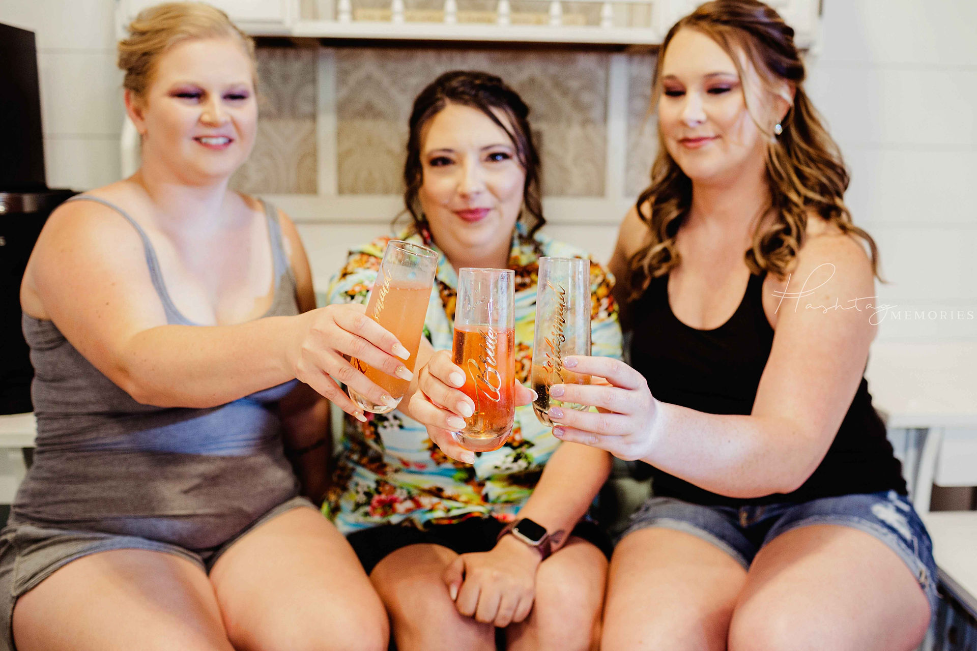 bridal party sits in bridal suite, champagne glasses huddled together in the center for a toast as the ladies circle around her to celebrate before the wedding