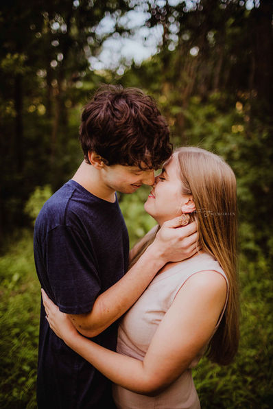 engaged couple kisses before indianapolis wedding during moody, romatice engagement photo session in Noblesville, Indiana