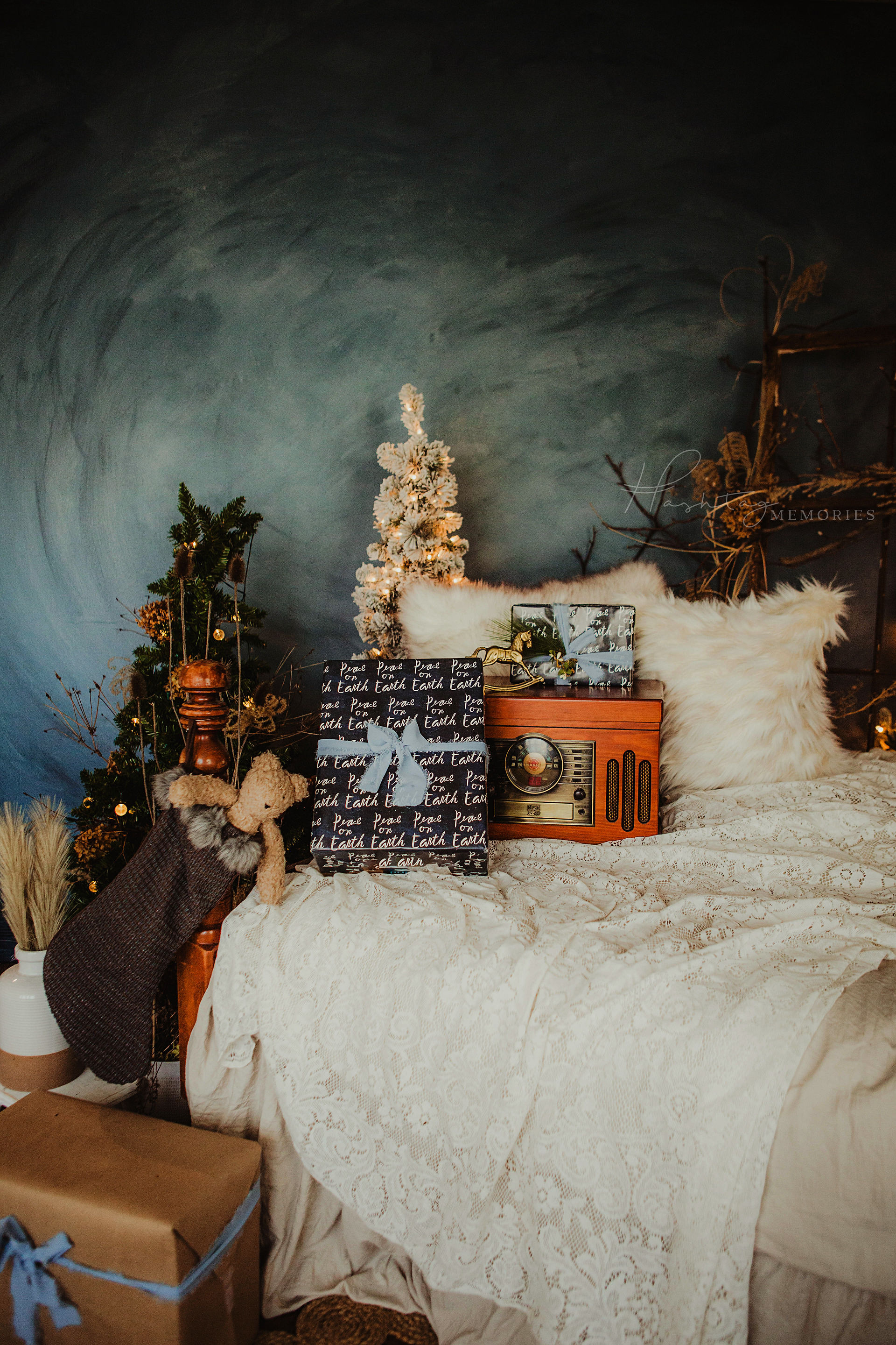 christmas bed photo set for holiday christmas minis in central indiana, vintage record player, wrapped gift boxes and a teddy in a christmas stocking decorate the bed with christmas tress behind