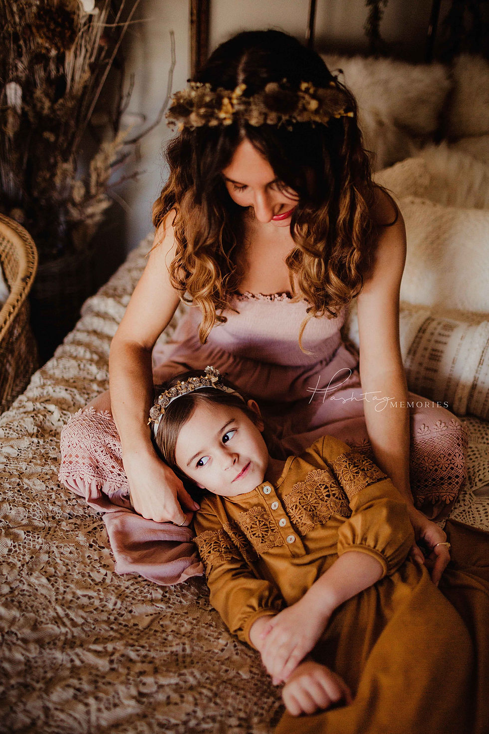 mother in boho flowy pink dress holding daughter on lace bedding during boho mommy and me photo session in tipton indiana