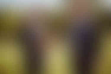 groom in black suite with grey vest enjoys a beer in his hobbit inspired mug with best man after wedding ceremony in southern indiana