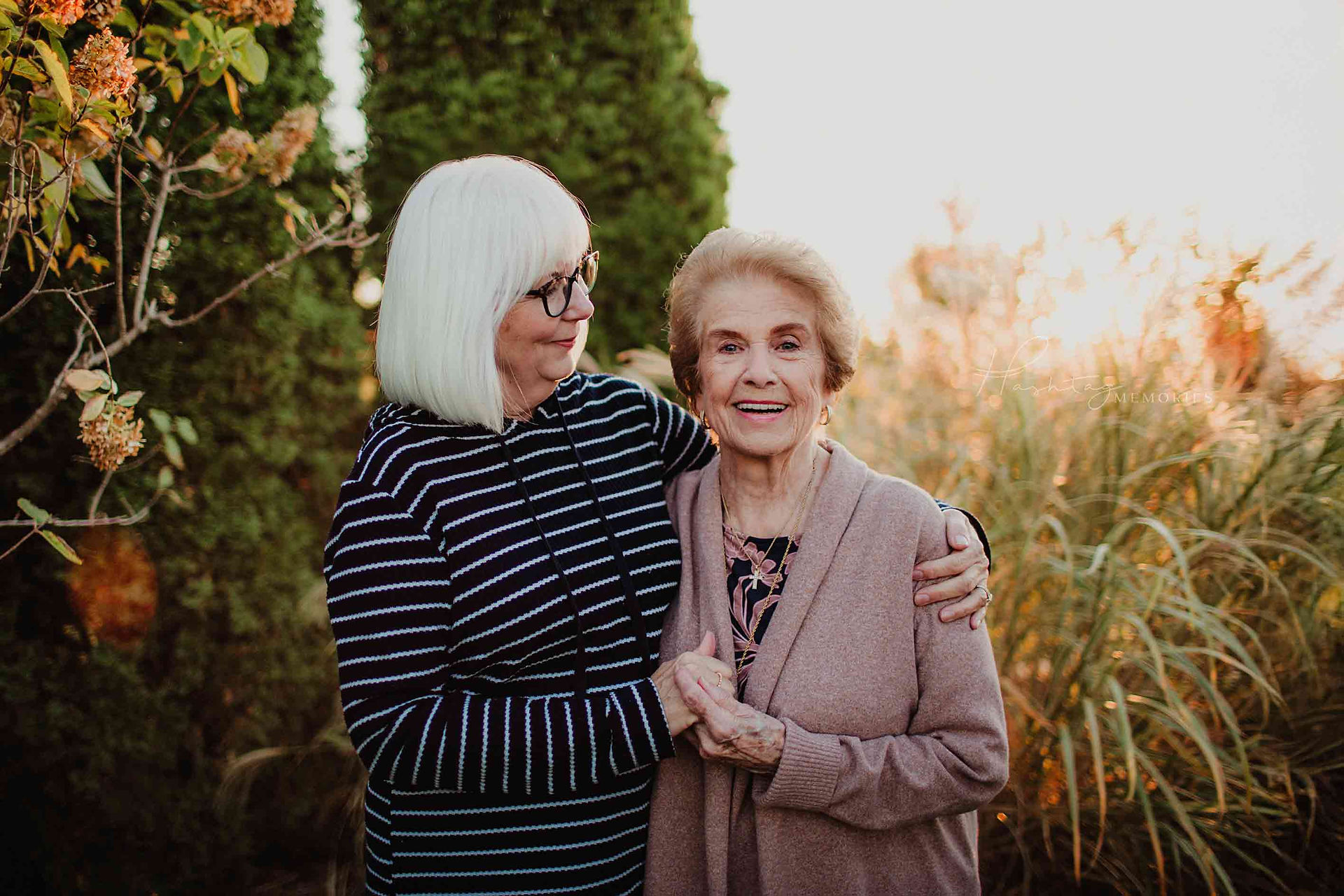Women hugs her mother in front of fall grasses during family photography session at coxhall gardens