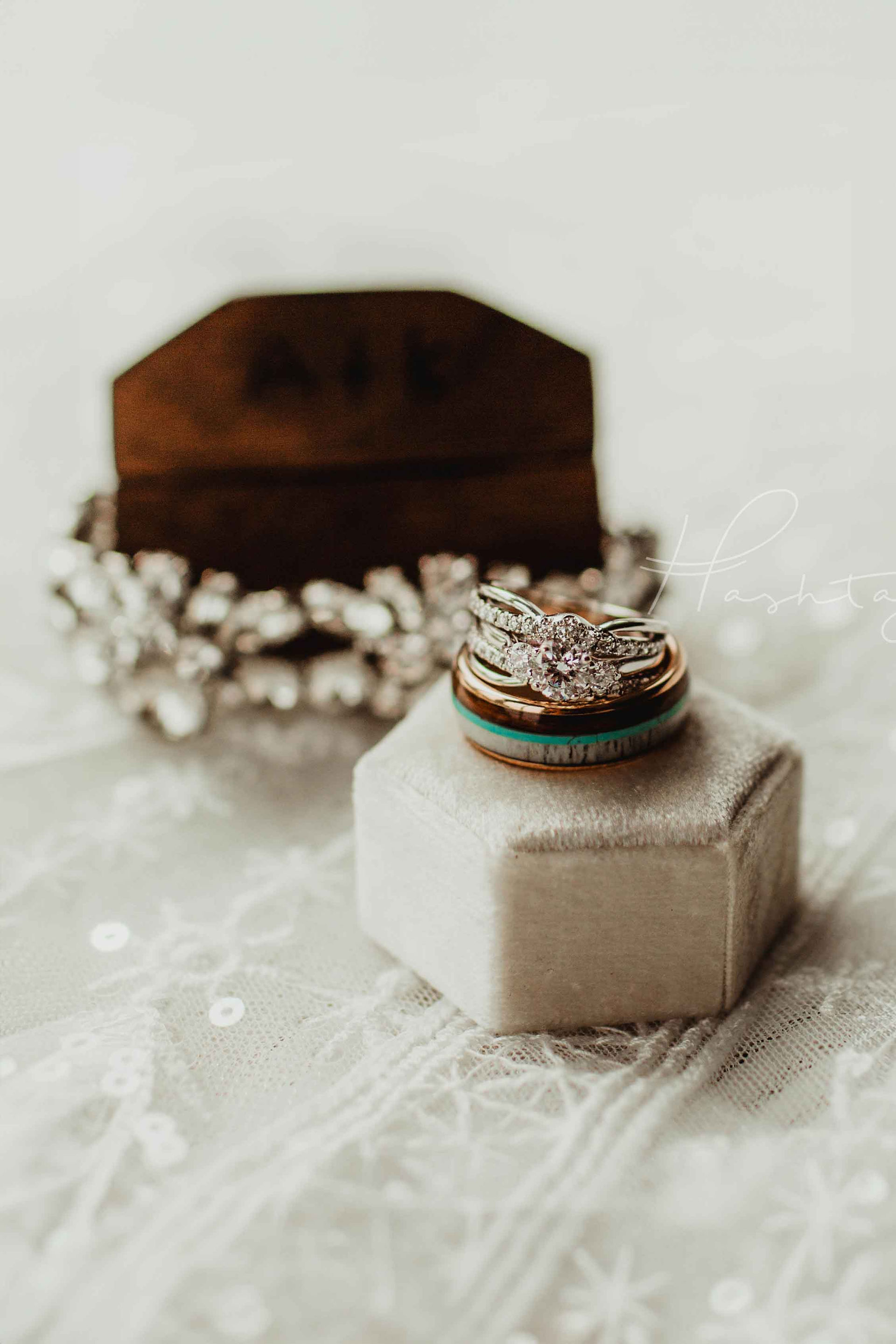 wedding rings stacked on white ring box on wedding day, groom's ring is wood inlay