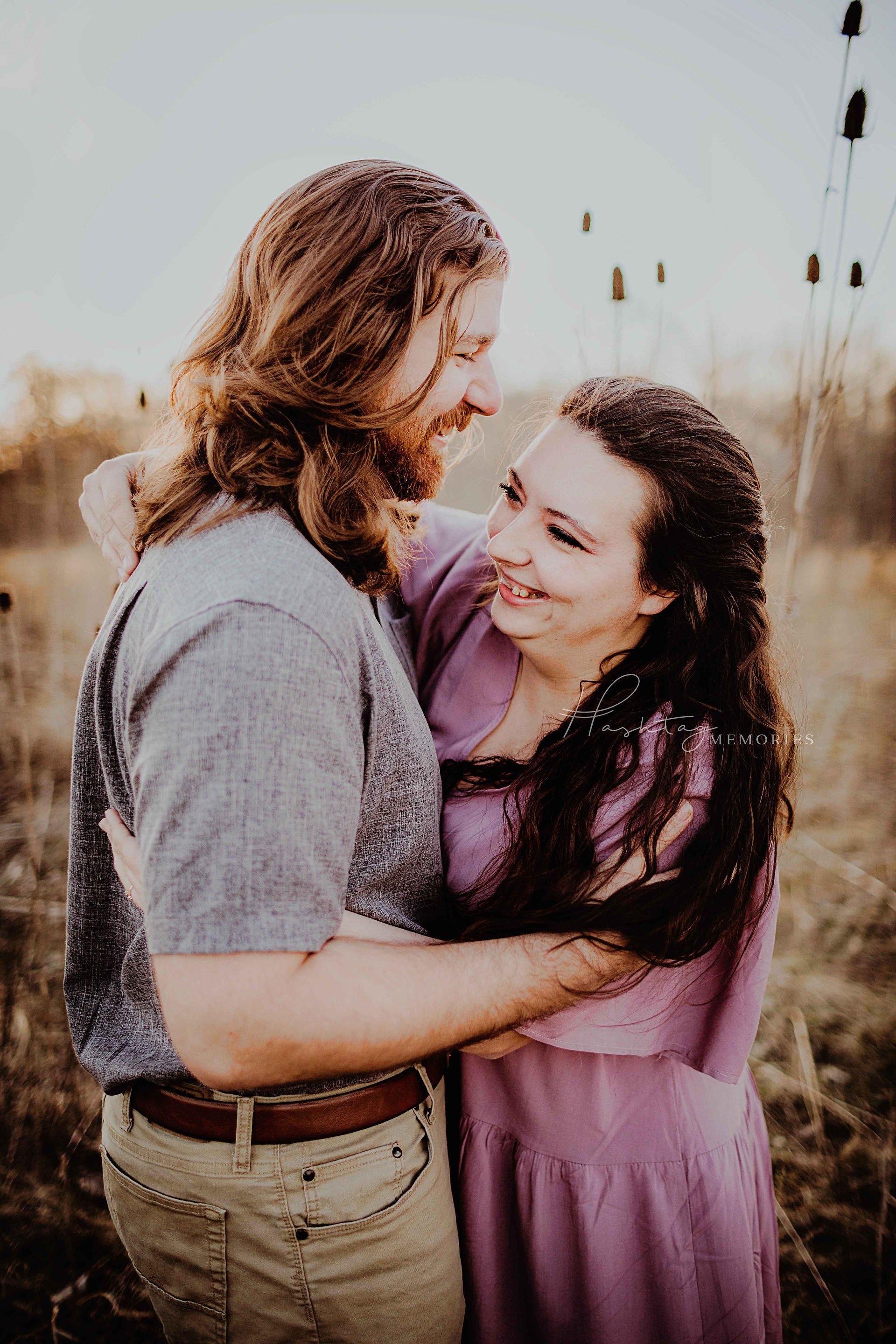 bride to be snuggles groom to be in winter golden field wearing purple plus size boho dress 