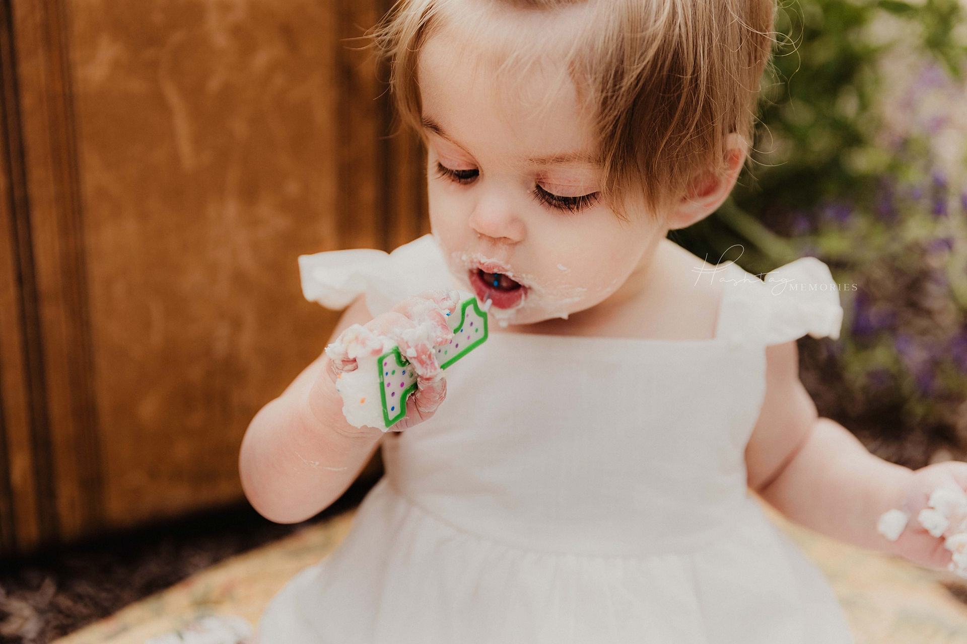 baby girl plays with birthday candle on her first birthday during family photos