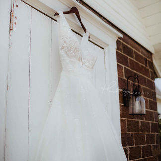 sparkle wedding dress hanging on barn door with red brick and vintage rustic details