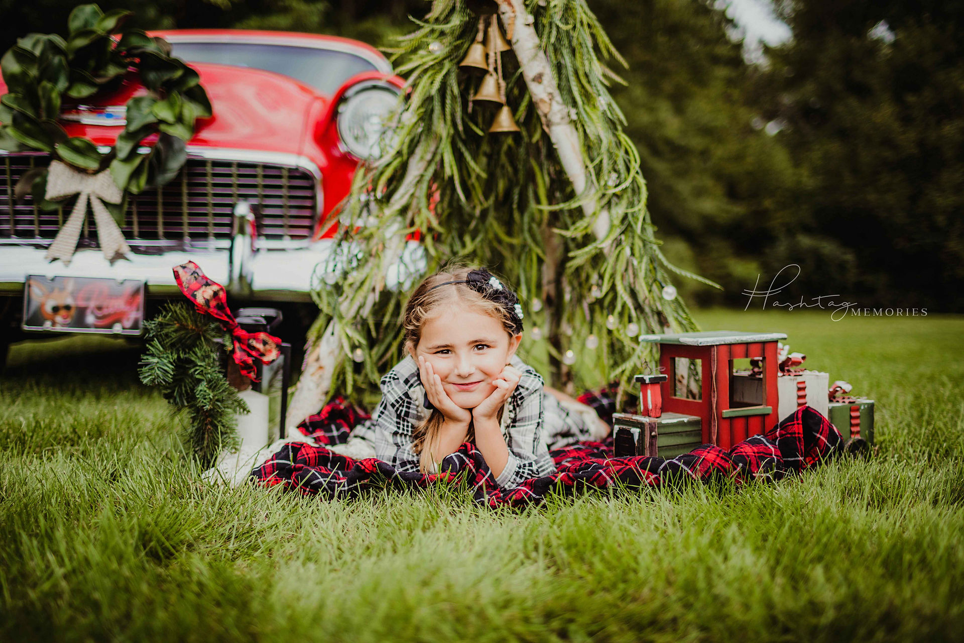 2022 christmas mini photos near me in central indiana, little girl stands dressing ladder christmas tree next to classic car with xmas decor around