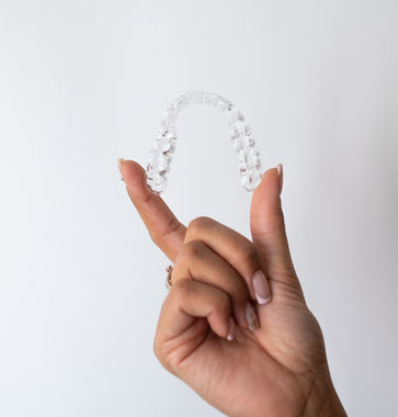 Hand hält eine transparente Zahnschiene vom Dentallabor Luxemburg