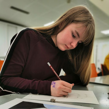 Tyttö piirtämässä pöydän ääressä muotokuvaa kansanedustaja Mikko Savolasta.