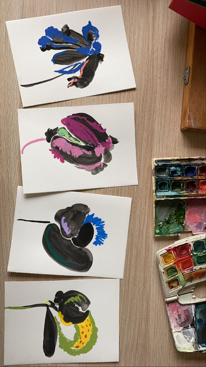 a bunch of paintings on a table with a box of watercolors