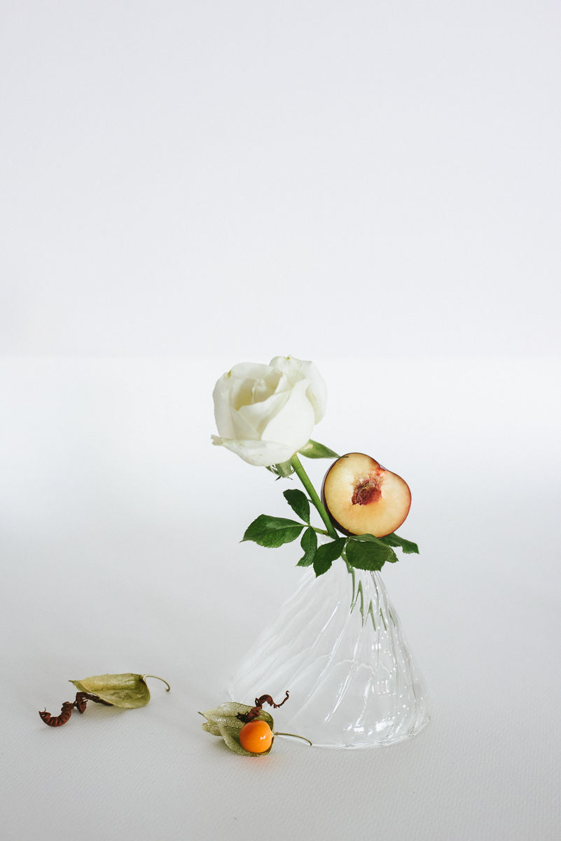 a white rose and a peach in a clear vase
