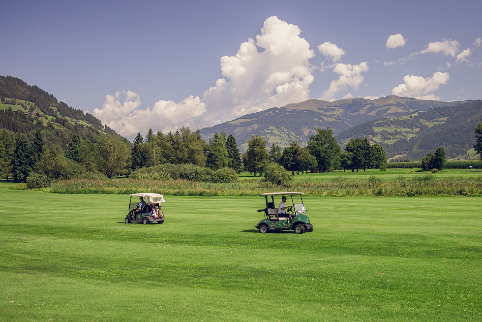 Golfcarts auf dem Golfplatz vor Bergkulisse – HELIGOLF