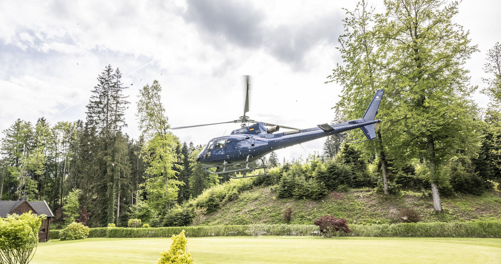Blauer Hubschrauber im Anflug auf einen Golfplatz – HELIGOLF