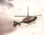 grüner Helikopter mit rote Streifen schwebt bei bewölktem Himmel