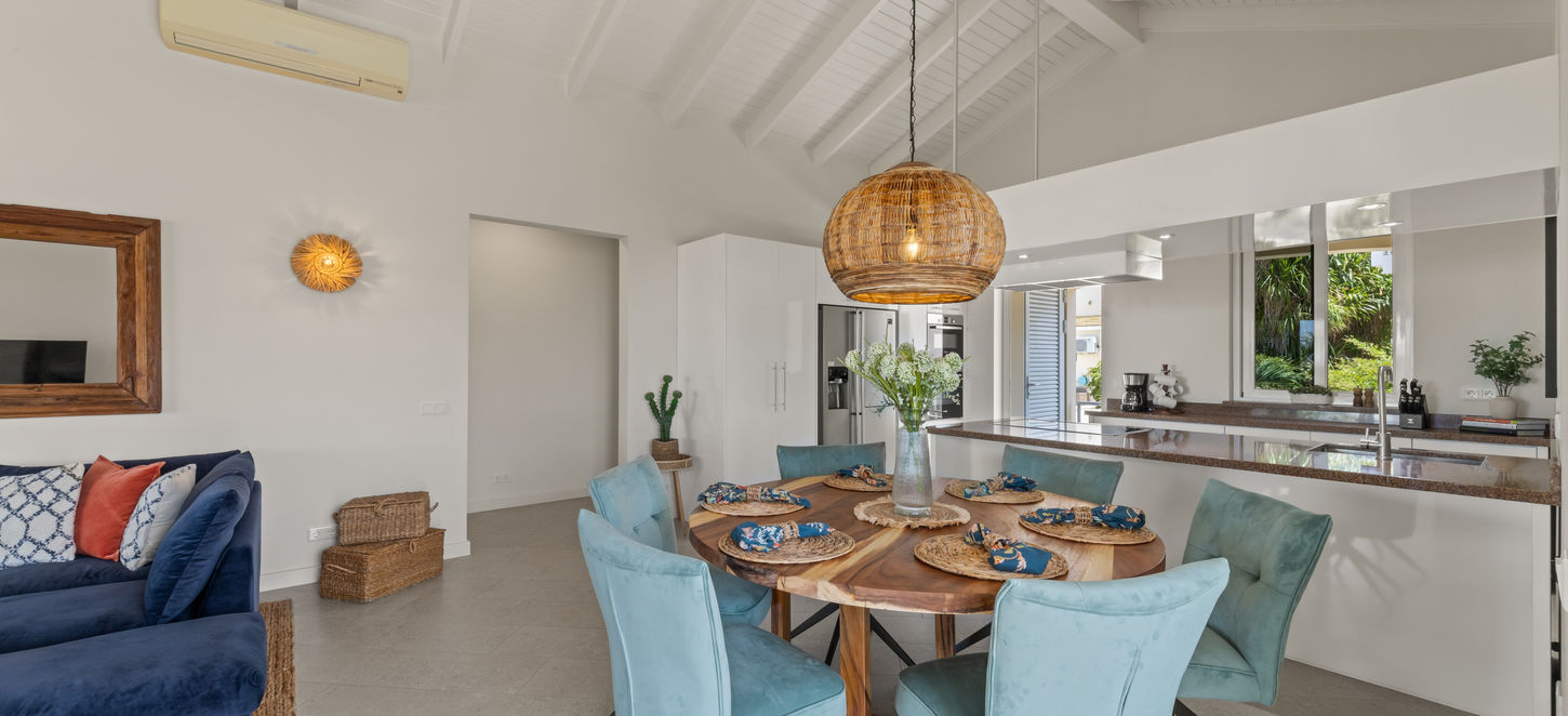 Open dining area with natural textures and high ceilings for island elegance.