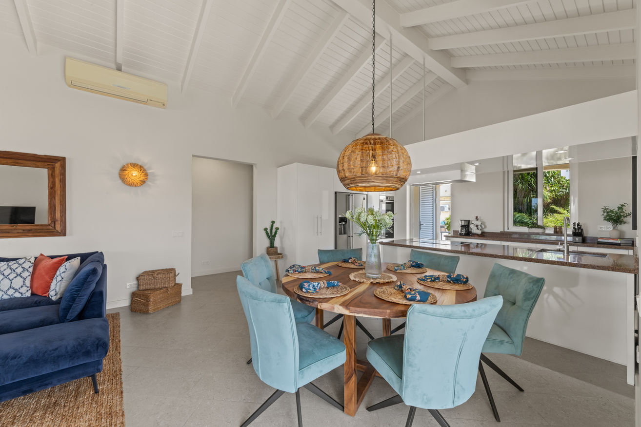 Open dining area with natural textures and high ceilings for island elegance.
