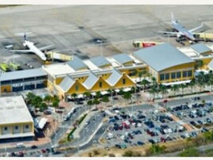Aerial view of Hato airport terminal with parked airplanes, yellow buildings, and a crowded parking lot.