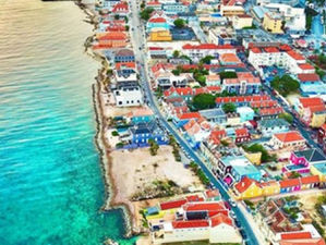 Aerial view of Willemstad, Curaçao’s colorful waterfront buildings along St. Anna Bay under bright tropical skies.
