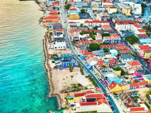 Aerial view of Willemstad, Curaçao’s colorful waterfront buildings along St. Anna Bay under bright tropical skies.
