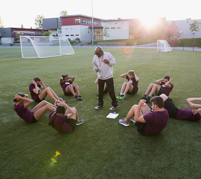 Team Practice sitting in a circle doing sit ups with the coach in the middle