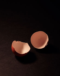 Cáscaras de huevo sobre fondo oscuro en una composición editorial de restos y presencia cotidiana.