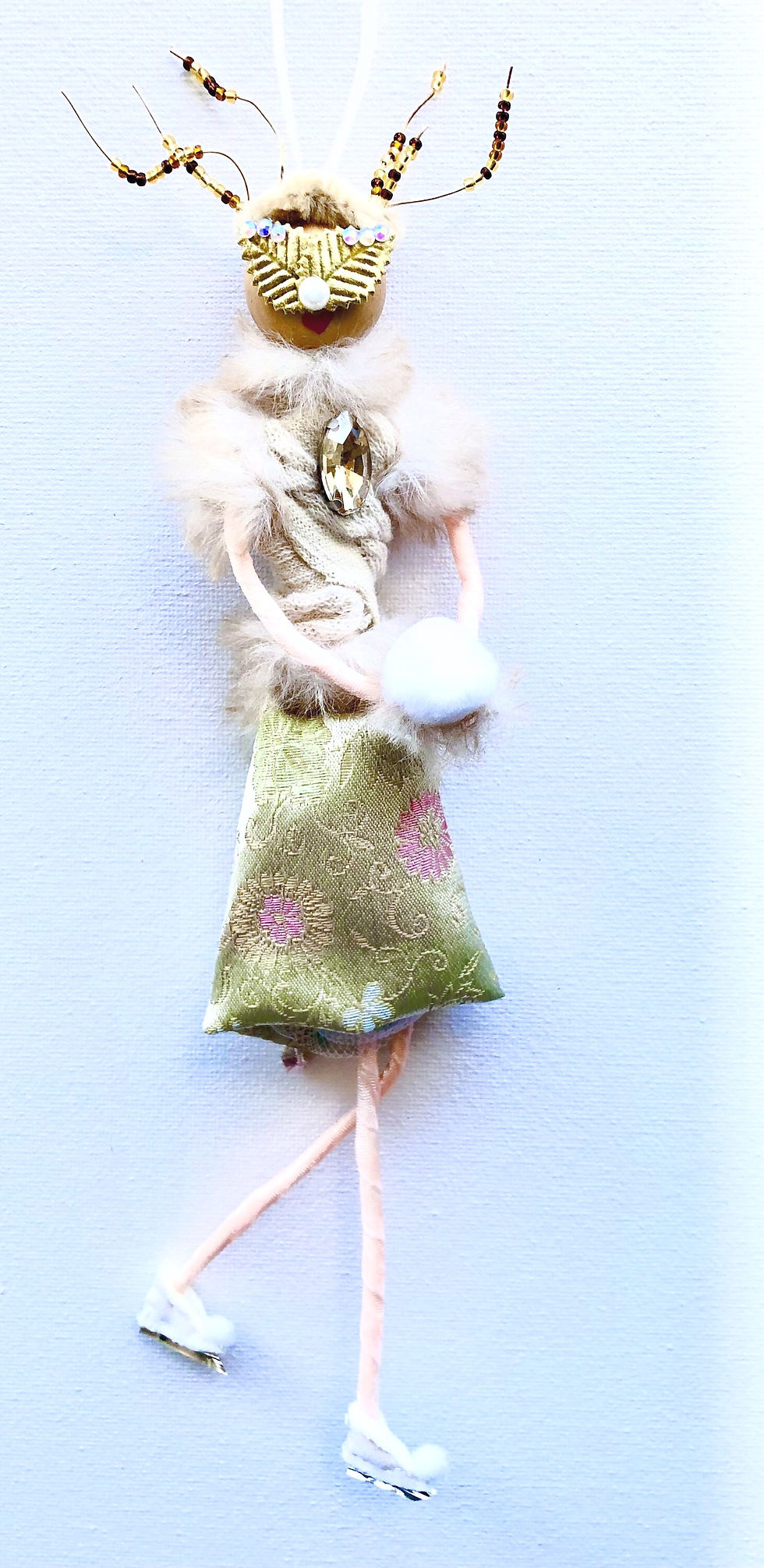ice skating reindeer doll adorned with skates, a white hand warmer, and gold details full body view