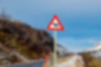 Wildlife warning sign on the E6 road in Norway, alerting drivers to reindeer crossing in a snowy mountain area.