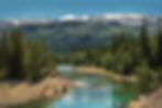 Scenic river landscape in Norway surrounded by forests and snow-capped mountains.