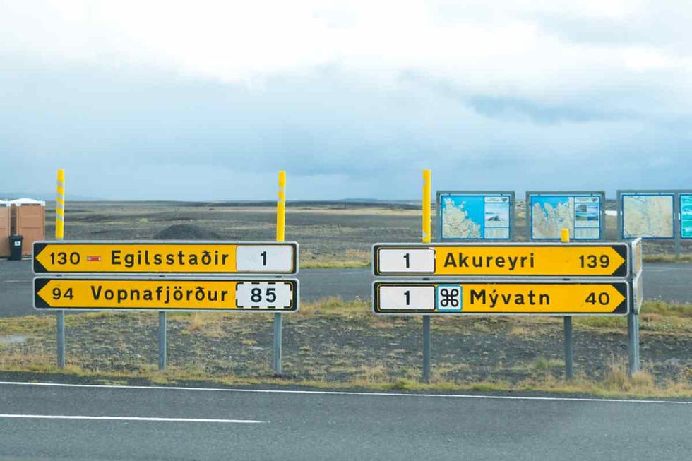 Plano detalle de señales de tráfico direccionales en una carretera asfaltada islandesa con su característico color amarillento y los números de las carreteras a las que hacen referencia.