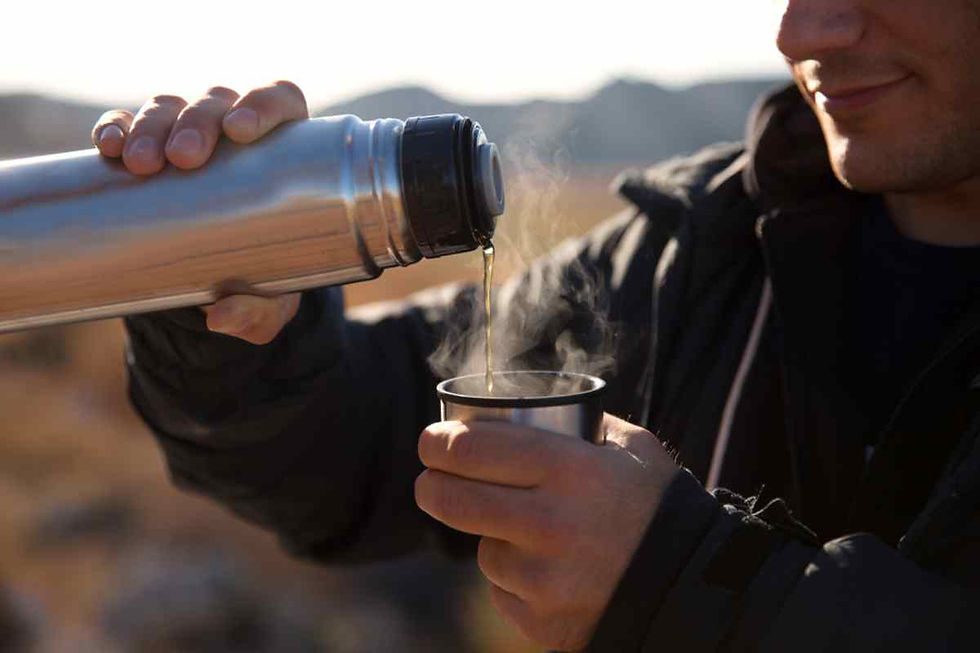 Dettaglio di un uomo che tiene in mano un thermos con acqua calda mentre la versa in un bicchiere.