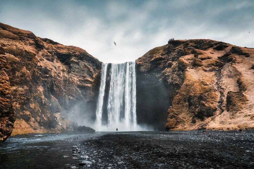 Cascada de Skógafoss cayendo en un amplio cortinón entre laderas doradas.