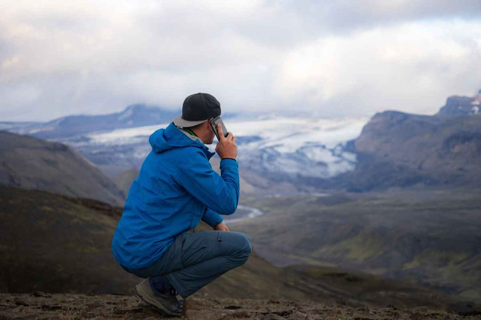 Un hombre con gorra y chaqueta azul llama por teléfono mientras se pone de cuclillas.